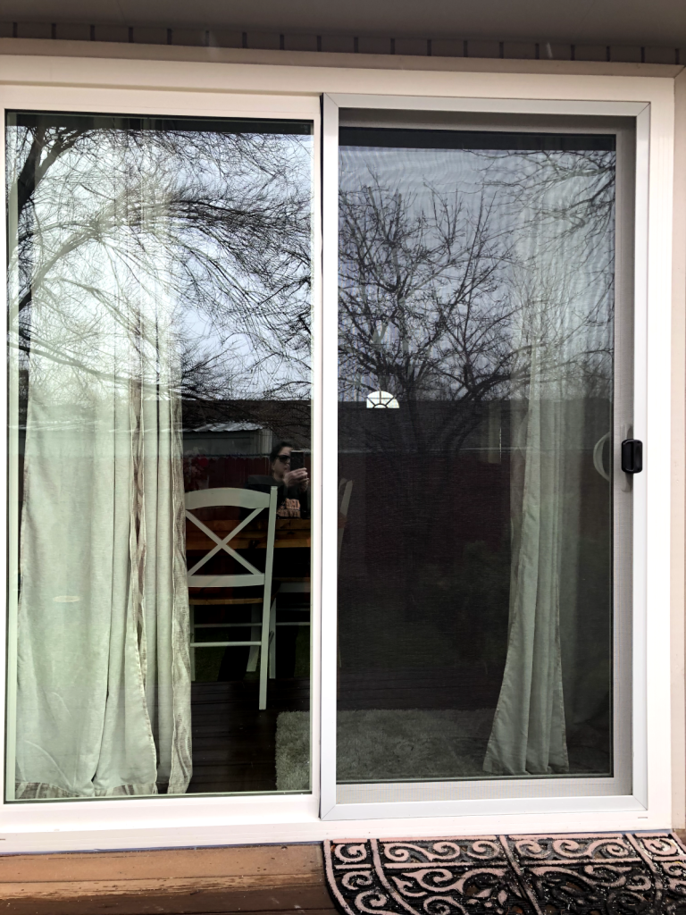 Sliding door with sheer curtains and trees.