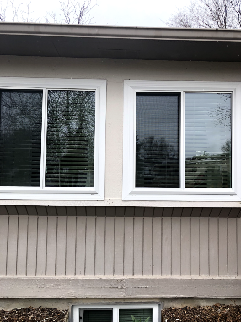 Two windows with blinds, beige wall