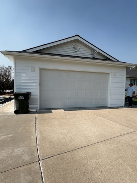 White garage with green trash can