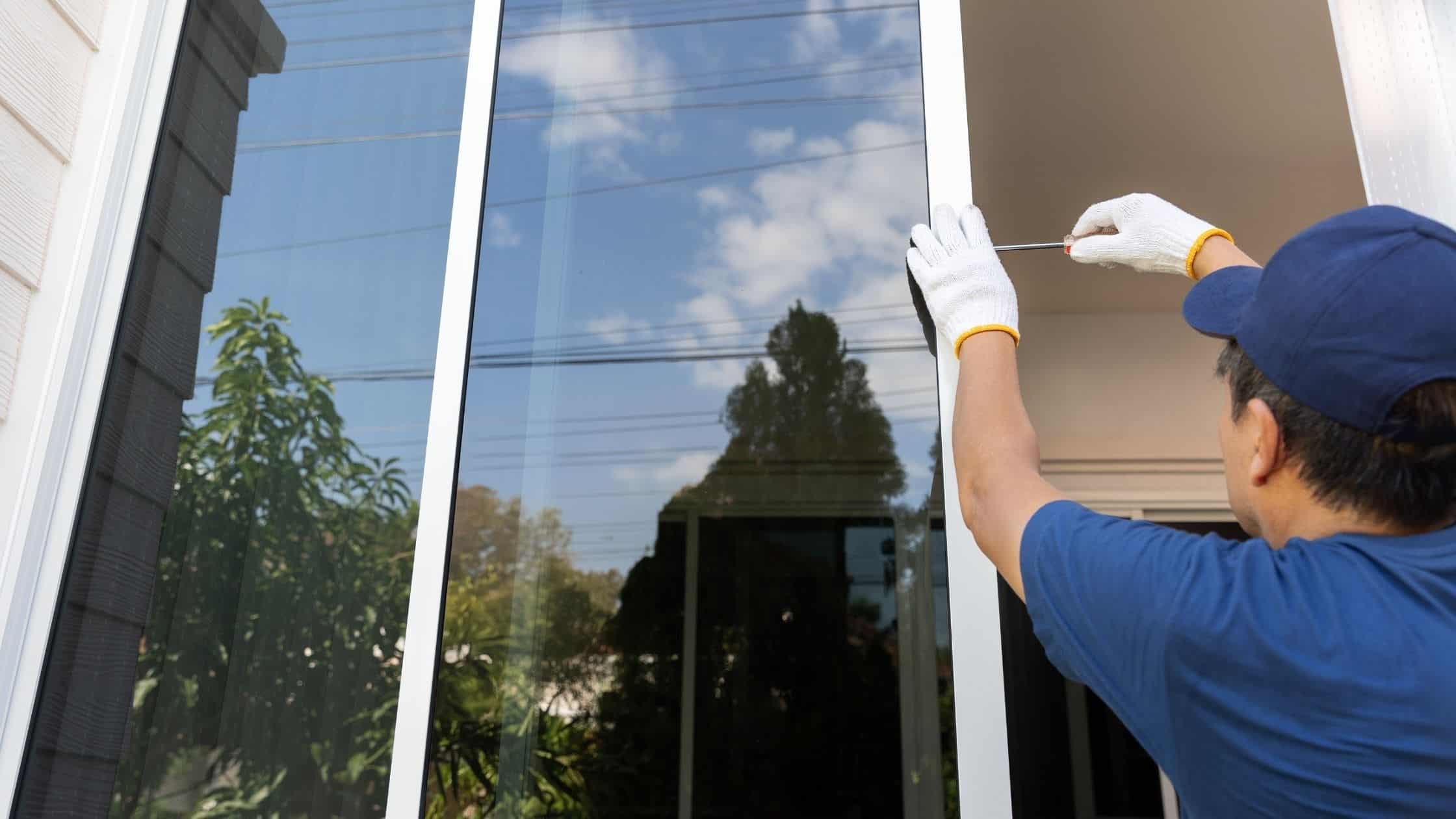 Technician installing a window with a screwdriver on a modern home exterior.